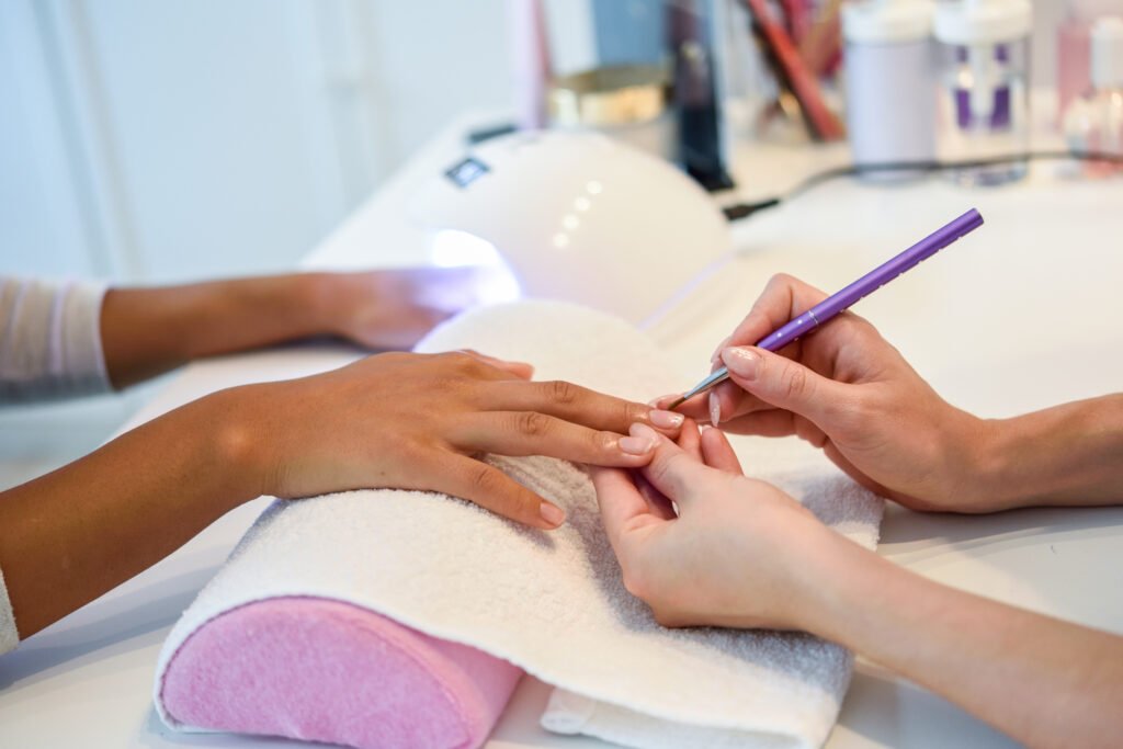 Nail designer profissional fazendo as unhas de sua cliente.