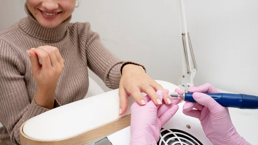 Manicure fazendo as unhas e sua cliente satisfeita com o resultado.